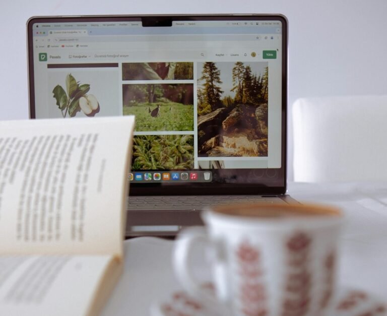Cozy setup with a laptop, open book, and coffee cup on a white table.